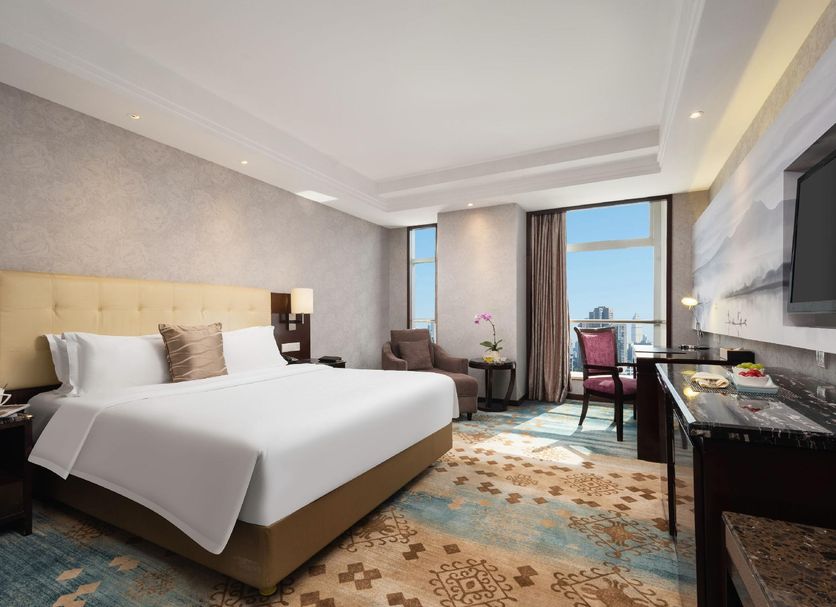 Huihao Hotel Wuhan guest room with king bed, city view window, desk and seating area