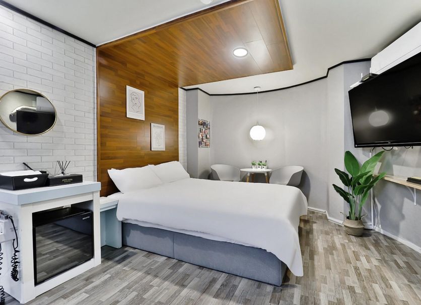 Hotel Atti Incheon guest room with bed, wall-mounted TV, seating area, and wood ceiling detail
