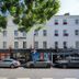 Easyhotel Paddington in London with white facade, street-level entrance, parked cars and tree shade