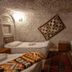Seven Rock Cave Hotel in Göreme cave-style guest room with three single beds and patterned rug