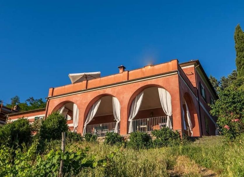 Agriturismo Cerrolungo in La Spezia, red hillside villa with arched balconies and garden