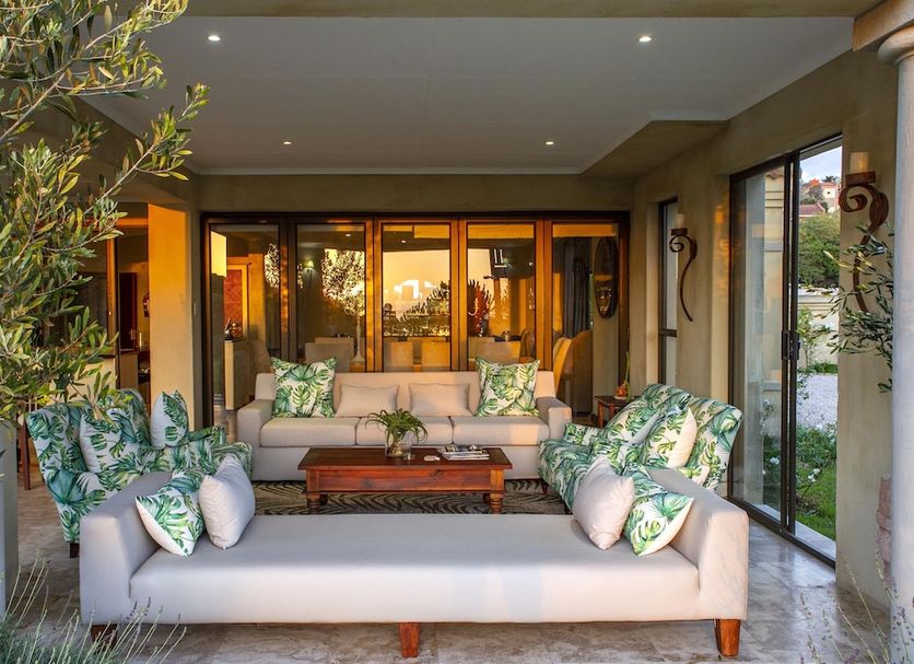 Supertubes Guesthouse in Jeffrey’s Bay outdoor lounge with sofas, tropical cushions and sliding glass doors