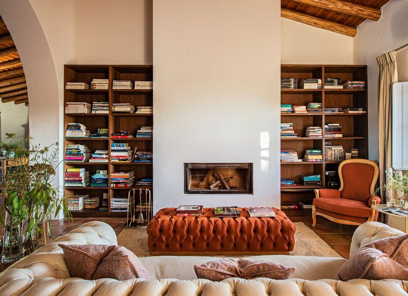 Herdade da Malhadinha Nova lounge in Beja with bookshelves, fireplace and tufted ottoman