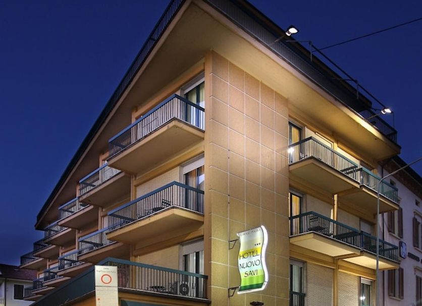 Hotel Nuovo Savi in Montecatini Terme, corner exterior with balconies and lit ground-floor restaurant at night