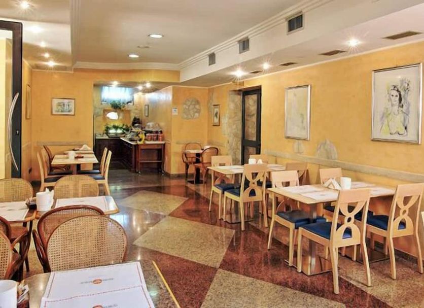 Hotel Aurora in Tivoli dining room with tables, chairs, warm lighting and buffet area