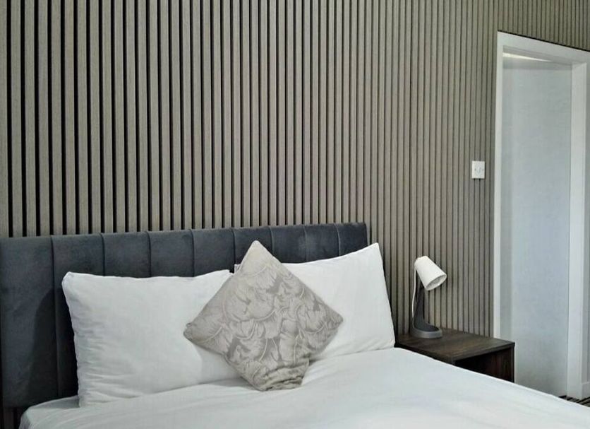 Kings Park Hotel Glasgow room with bed, patterned cushion, bedside lamp and slatted feature wall