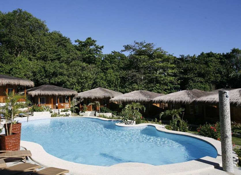 Magic Oceans Dive Resort in Anda: tropical outdoor pool with thatched cabanas and lush greenery
