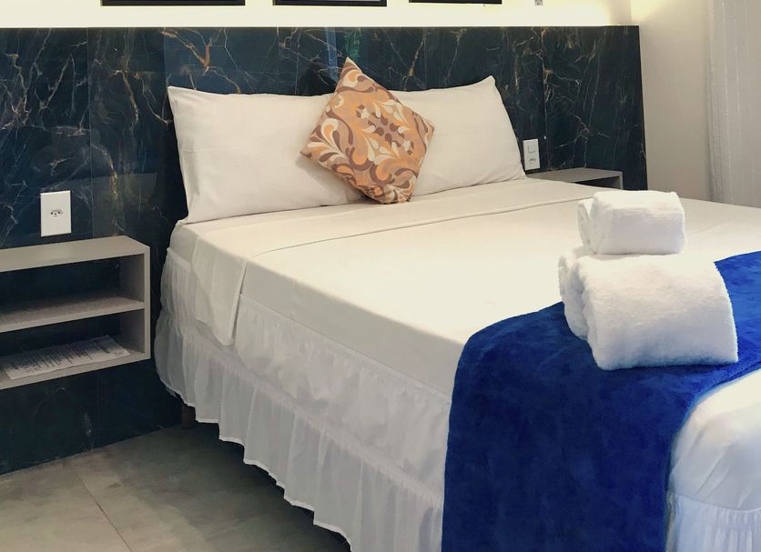 Pousada Gente Bonita La Mansion guest room with bed, wall art, air conditioner and folded towels in Búzios