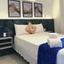 Pousada Gente Bonita La Mansion guest room with bed, wall art, air conditioner and folded towels in Búzios