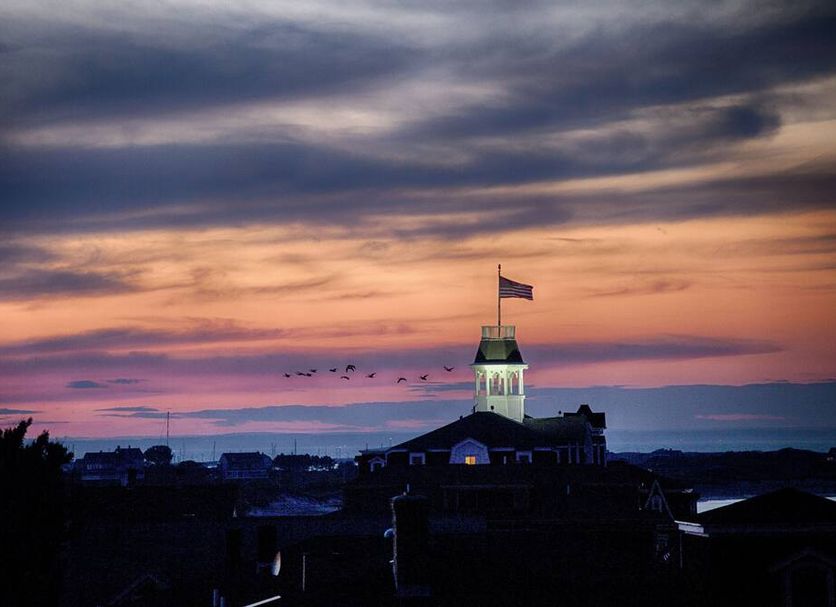 National Hotel in Block Island with sunset sky above the waterfront and a flag-topped tower