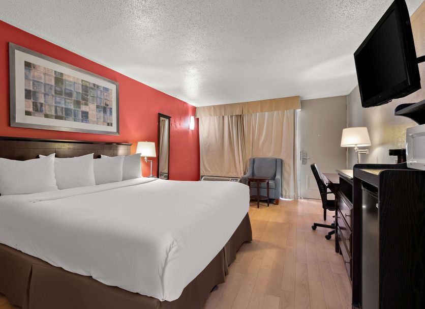 Quality Inn Wayne - Fairfield Area guest room with king bed, desk, chair and red accent wall in Wayne