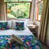 Villeta Resort Hotel in Villeta bedroom with double bed, tropical bedding, and garden view through large windows
