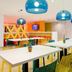 Ibis Styles Düsseldorf - Neuss dining area with white tables, colorful chairs and blue pendant lights