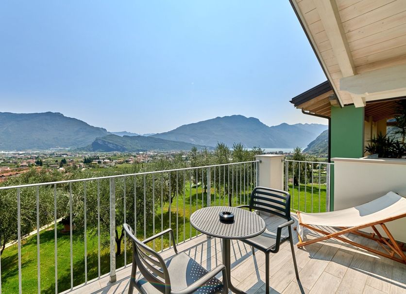 Maso Tobel Riva del Garda terrace with table, chairs and lounge chair overlooking mountains and lake views