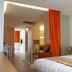 60 West Hotel Hong Kong room with bed, seating area, orange curtain, and city print wall art