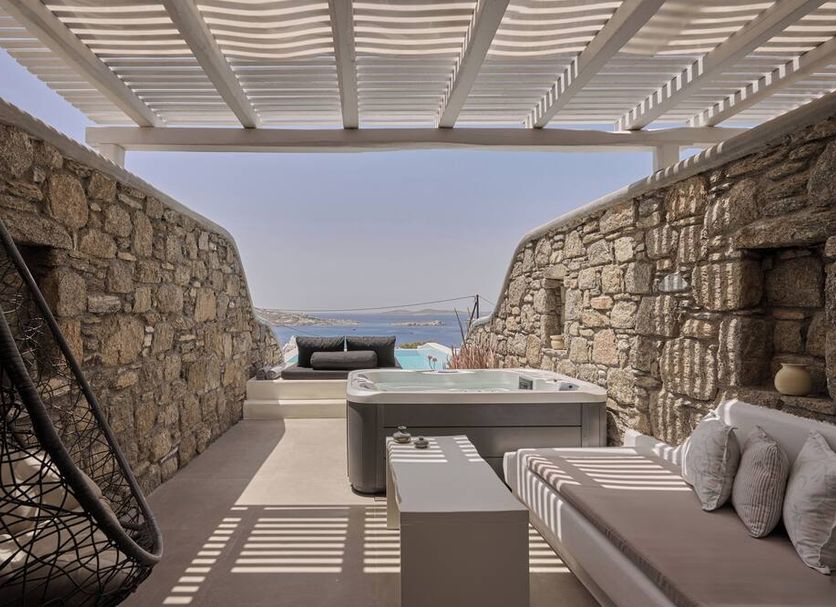 Balius Mykonos in Mykonos, stone terrace with hot tub, lounge bed and sea view