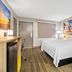 Days Inn by Wyndham Jacksonville NC room with king bed, palm-tree wall art, and wood-look floors