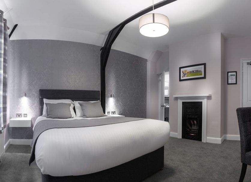 Qudos Salisbury guest room with king bed, curved ceiling, fireplace and modern gray decor