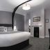 Qudos Salisbury guest room with king bed, curved ceiling, fireplace and modern gray decor