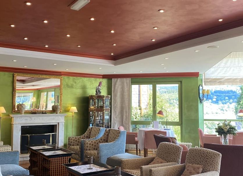 Le Manoir Au Lac in Gérardmer lounge with fireplace, patterned chairs, and lake-facing windows