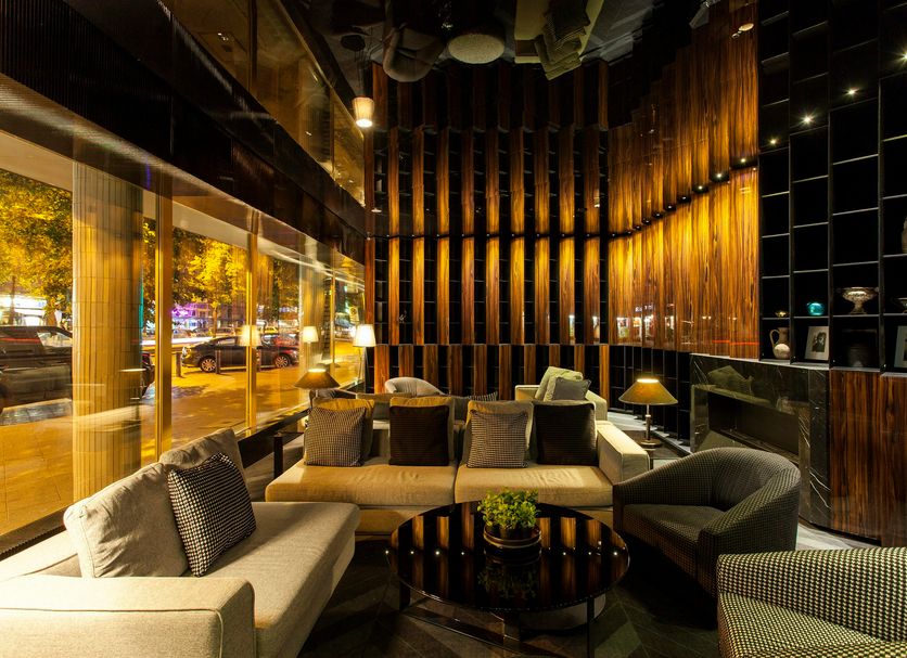 Quentin Boutique Hotel Berlin lobby lounge with curved seating, warm wood walls and city-view windows