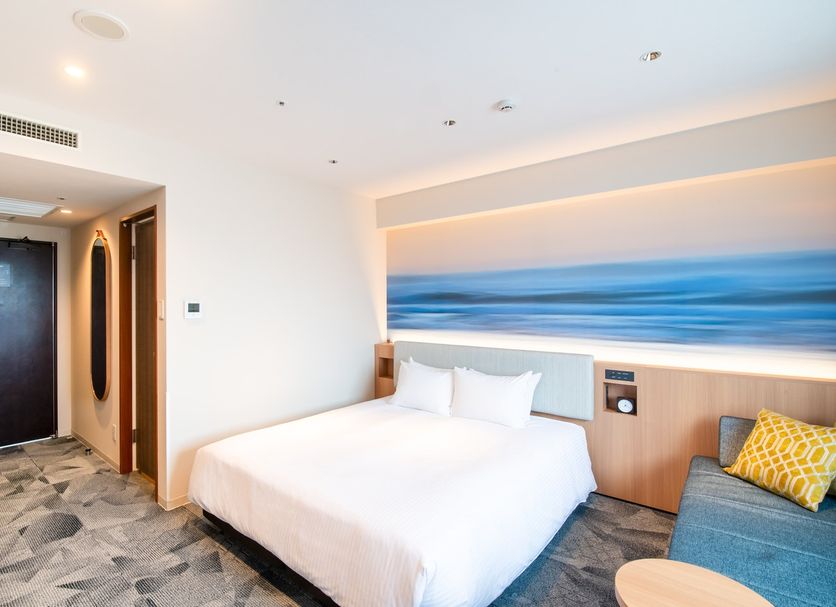 Richmond Hotel Miyazaki Ekimae guest room with bed and ocean-inspired wall art in Miyazaki