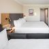 Holiday Inn London - Gatwick Airport By IHG room with two beds, wall-mounted TV and doorway to hall