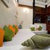 Villas Sur Mer in Negril guest room with twin beds, colorful pillows, and wood louvered windows