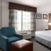 La Quinta Inn & Suites by Wyndham Bakersfield North guest room with king bed, teal chair, and window