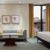 Hilton Kyiv room with sofa, coffee table, floor lamp, framed art and city views through tall windows