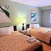 The Kingsley Suites in Kingsley guest room with two beds, window, bedside lamp and wall art
