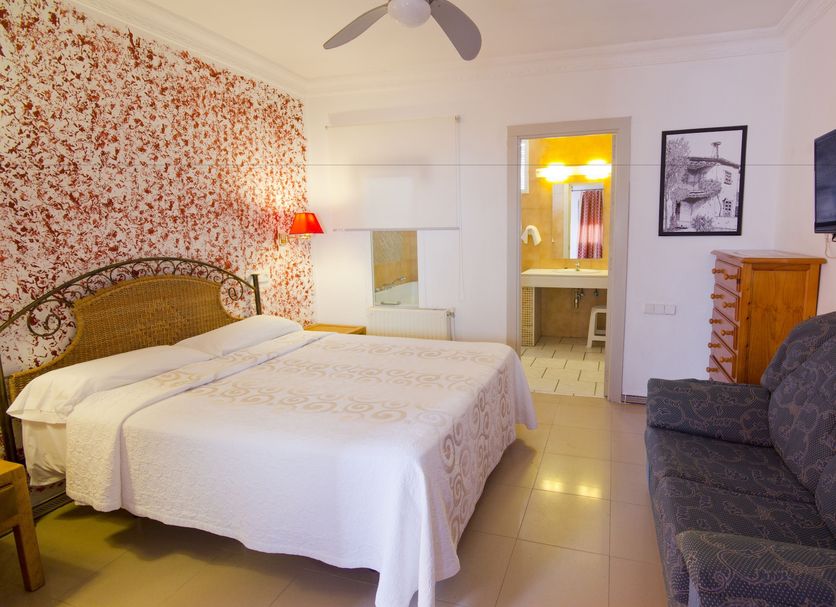 Hostal Nueva Andalucia room in Alcalá de Guadaira with double bed, sofa and wall-mounted TV
