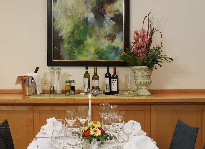 Stadthotel Oranienburg banquet table set with wine glasses, bottles and floral centerpiece in Oranienburg