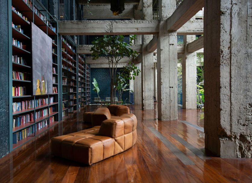 Stamba Hotel in Tbilisi lobby with tall bookshelves, leather seating and industrial concrete columns