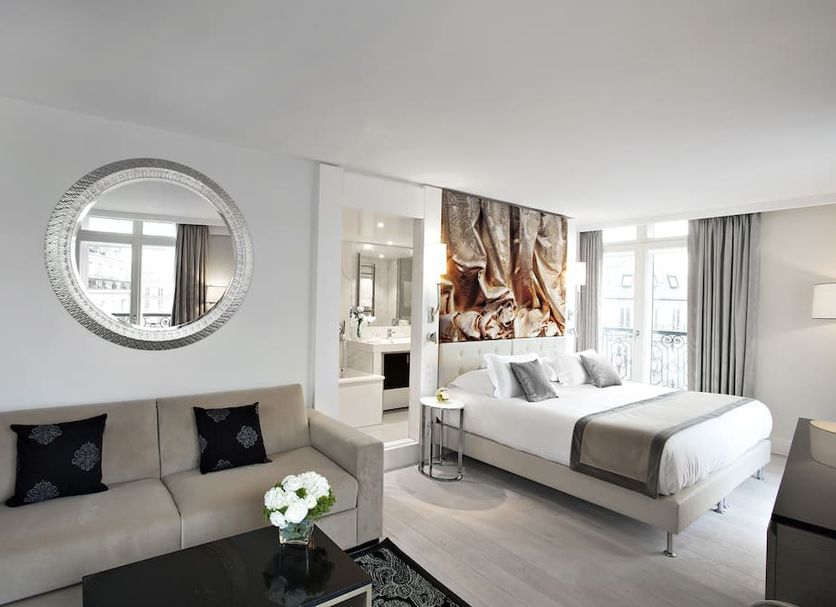 La Villa Haussmann Paris room with sofa, king bed, balcony doors and round mirror