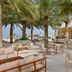 Waldorf Astoria Ras Al Khaimah beachfront terrace with palm trees, seating and open-air bar