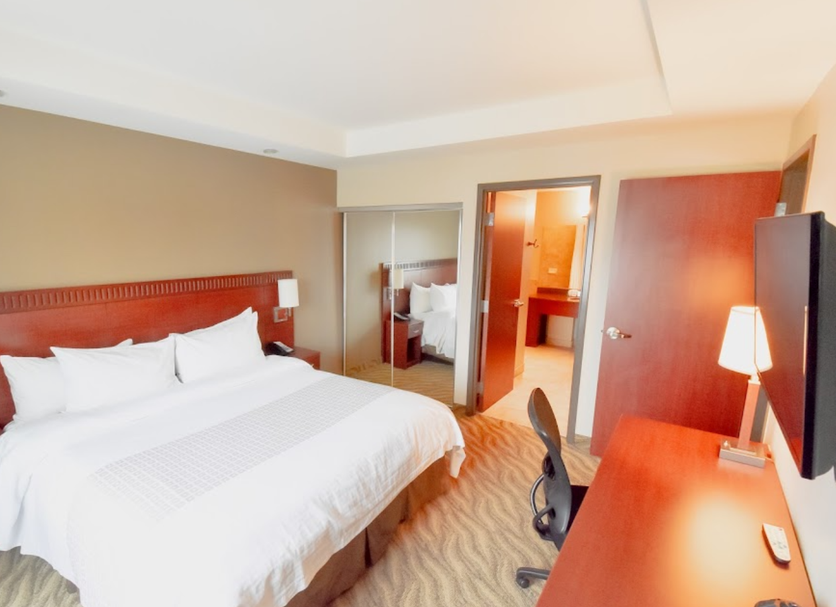 Canad Inns Destination Centre Garden City in Winnipeg guest room with king bed, desk and bathroom doorway