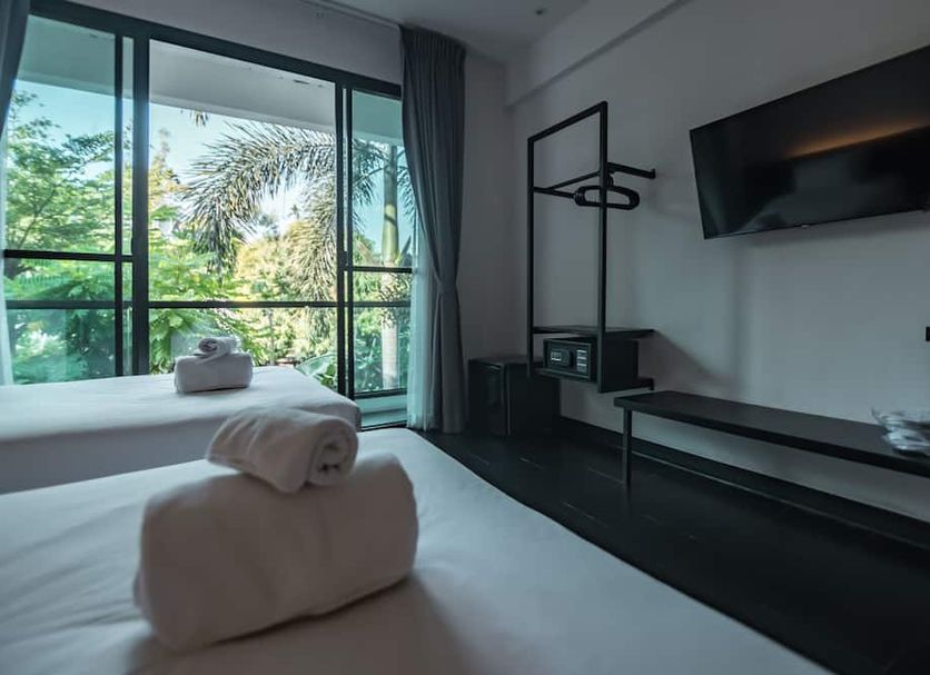 Iwualai Hotel Chiang Mai guest room with large garden-view windows and wall-mounted TV