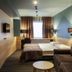 Ibis Styles Riga guest room with twin beds, sofa, and window with curtains in Riga