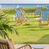 The Relais Cooden Beach in Bexhill-on-Sea with striped deck chairs on a seaside lawn and ocean view
