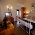 Bedroom at Bandarawela Hotel in Bandarawela with a white metal bed, wooden dresser, and armchair