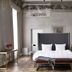 Hotel Pacai in Vilnius room with king bed, tall windows, ornate wall frieze, and armchair