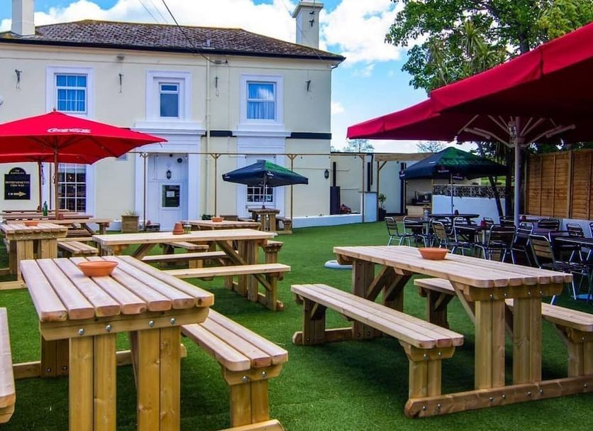 The Railway Inn in Brixham with outdoor picnic tables and umbrellas on a grassy patio
