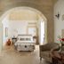 Palazzo Ducale Venturi bedroom with arched stone entry, bed, seating area and fireplace in Minervino di Lecce