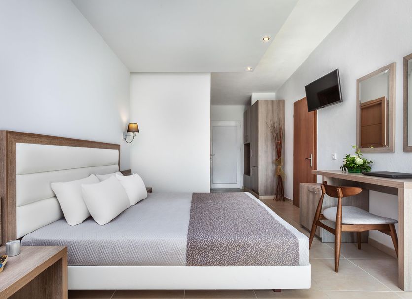 Iris Hotel Siviri guest room with bed, desk, wall-mounted TV and wardrobe