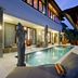 Sahaja Sawah Resort, Tabanan: courtyard pool beside villa rooms with loungers and a statue at dusk