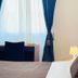 Novella Italy hotel room in Florence with bed, desk, and window with blue curtains