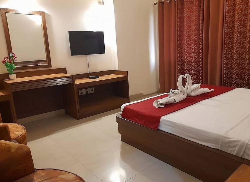 Hotel Maiden Residency room in Ghāziābād with double bed, TV, desk and red curtains