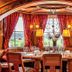 Schloss Hotel Holzrichter in Nachrodt-Wiblingwerde dining room with set table, arched windows and red drapes