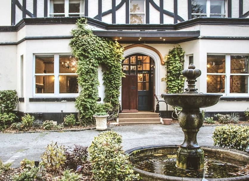 Brook Hall Hotel in Ellesmere Port with ivy-covered facade and decorative courtyard fountain